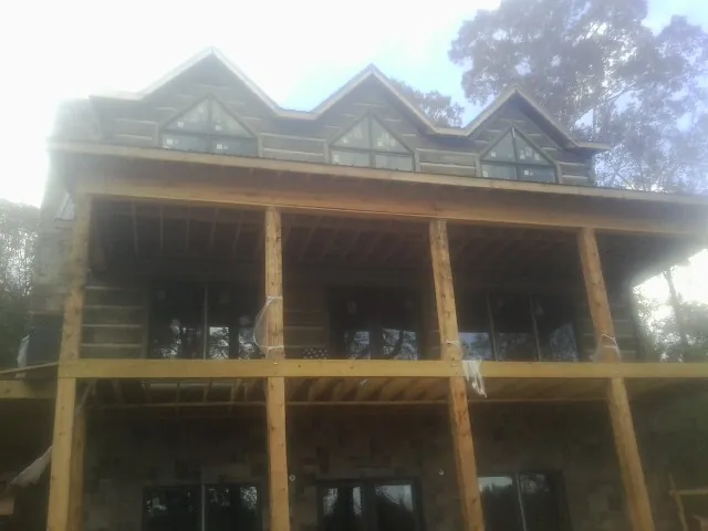 Dormers and porch framing on a large log home under construction — Roof Coating work by our crew in Port Chester