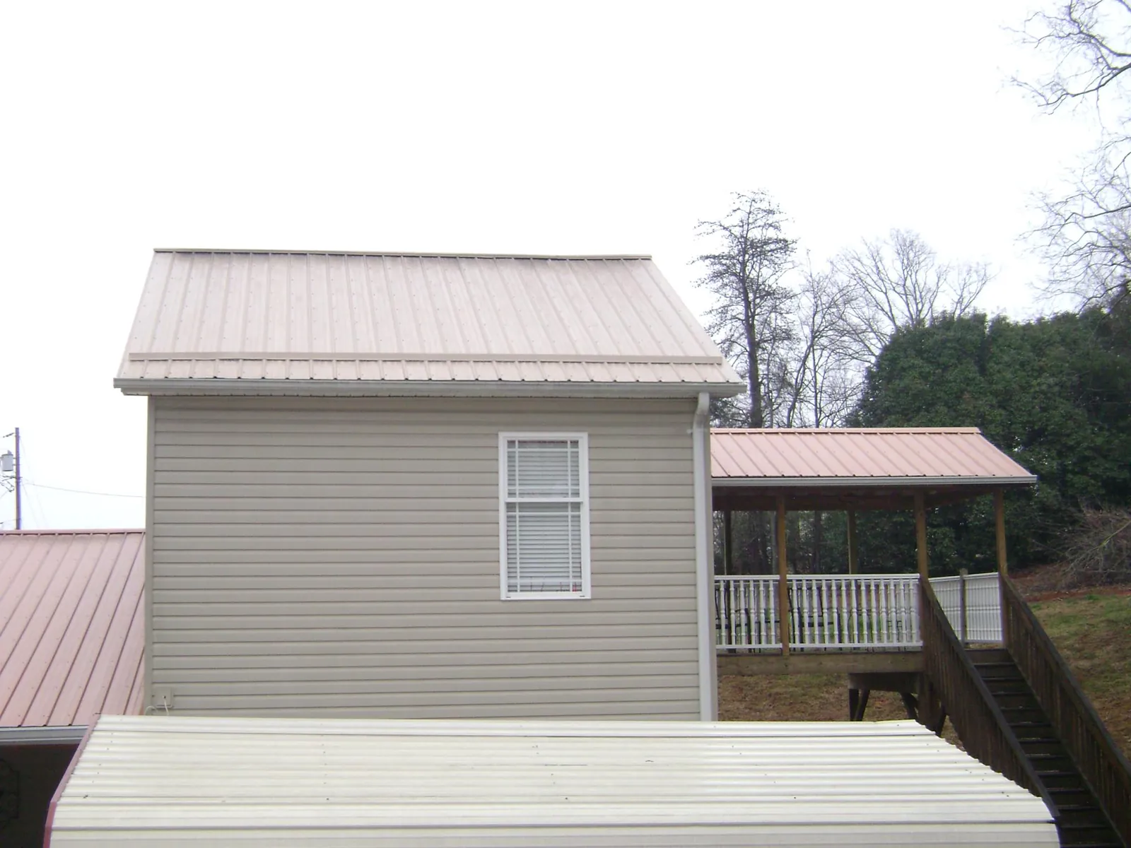 Tan metal roofs on a two story addition and attached porch, from a Roof Replacement job in Port Chester