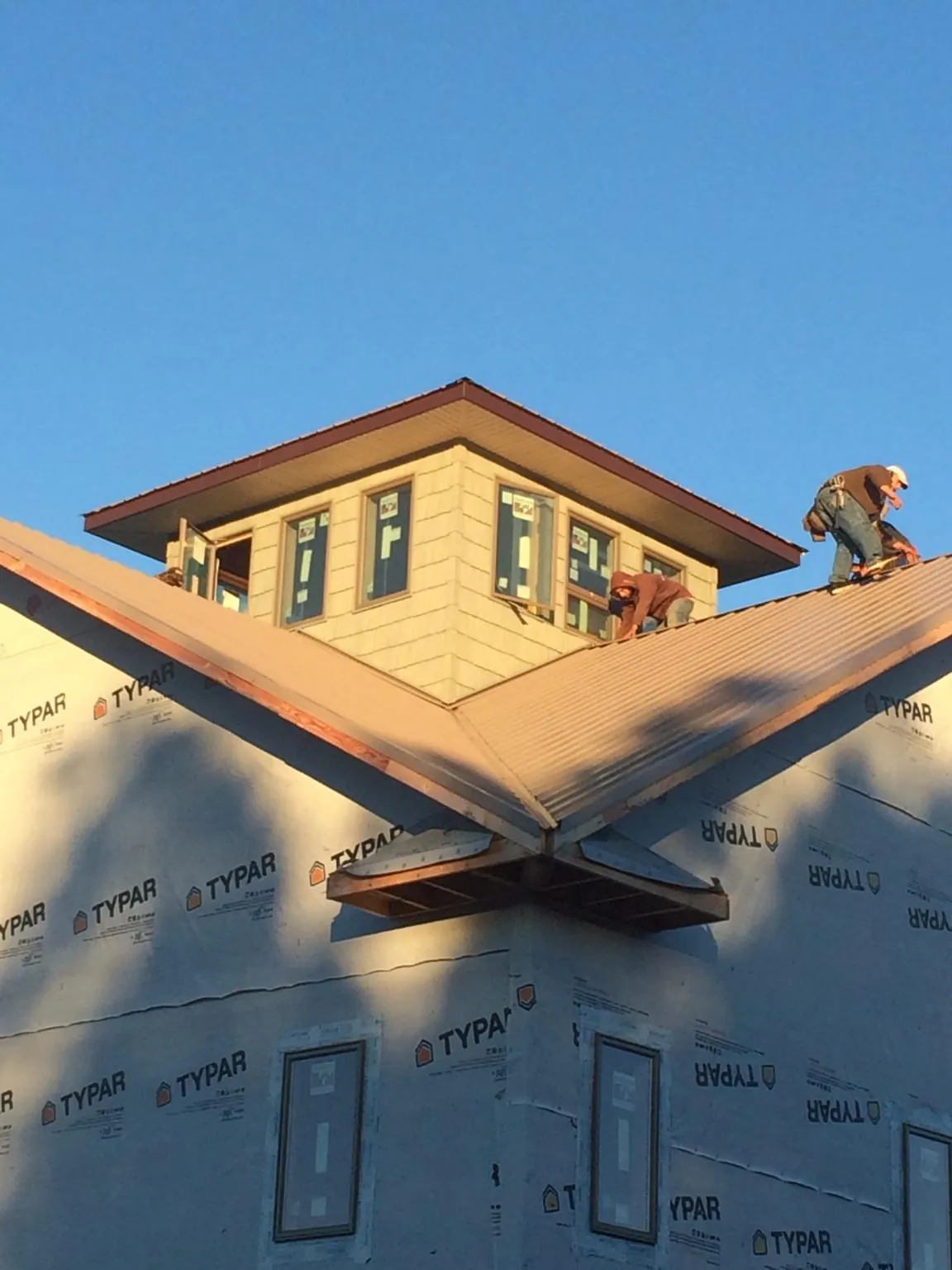 Roofers working around a rooftop cupola on a new metal roof at sunset — Roof Waterproofing in Port Chester by Roofing Brothers